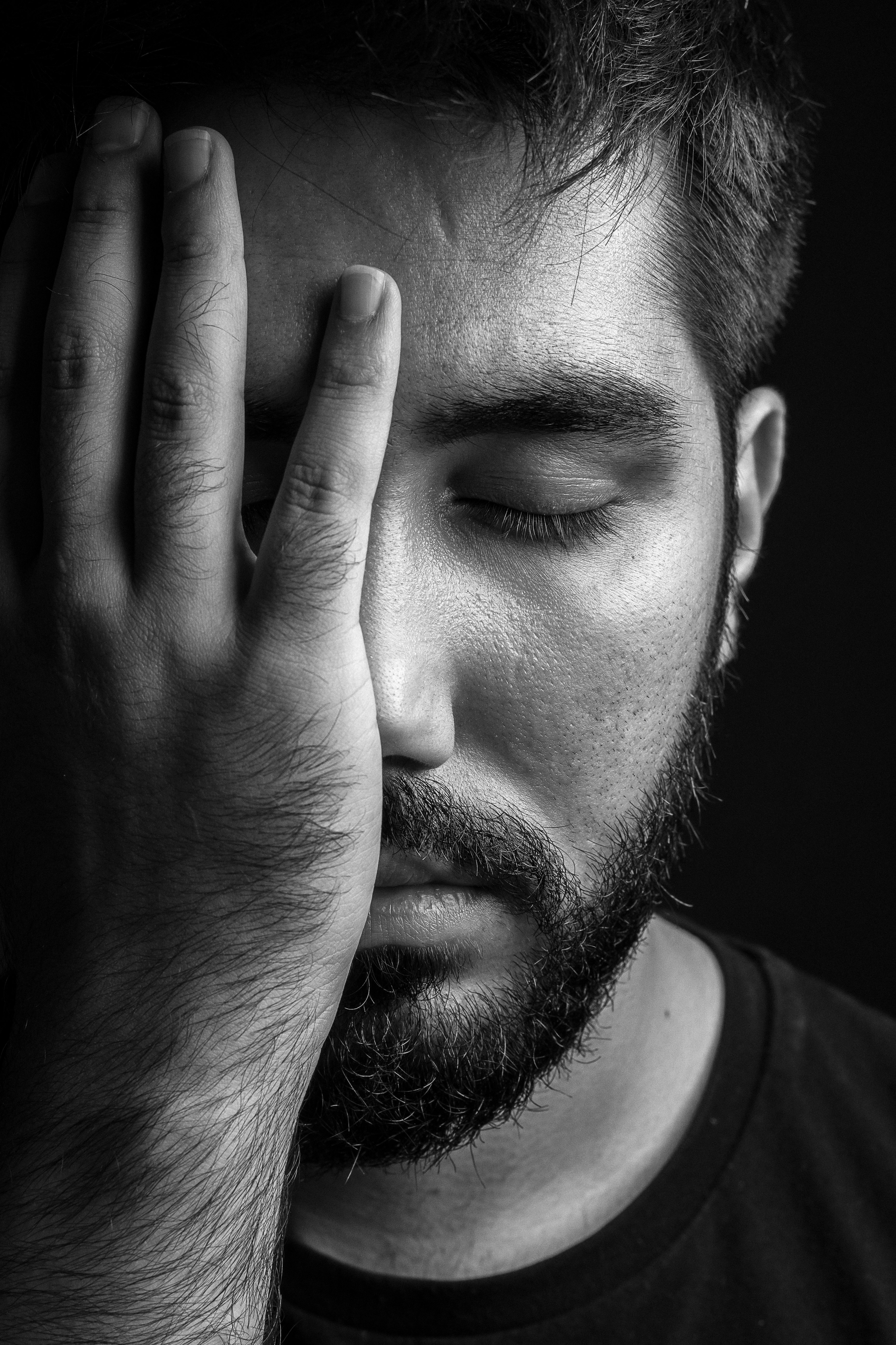 grayscale photo of man covering his face